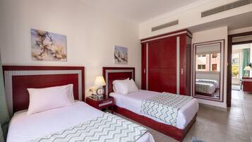 A hotel room with two beds, a large wardrobe, a mirror, and artwork on the walls.
