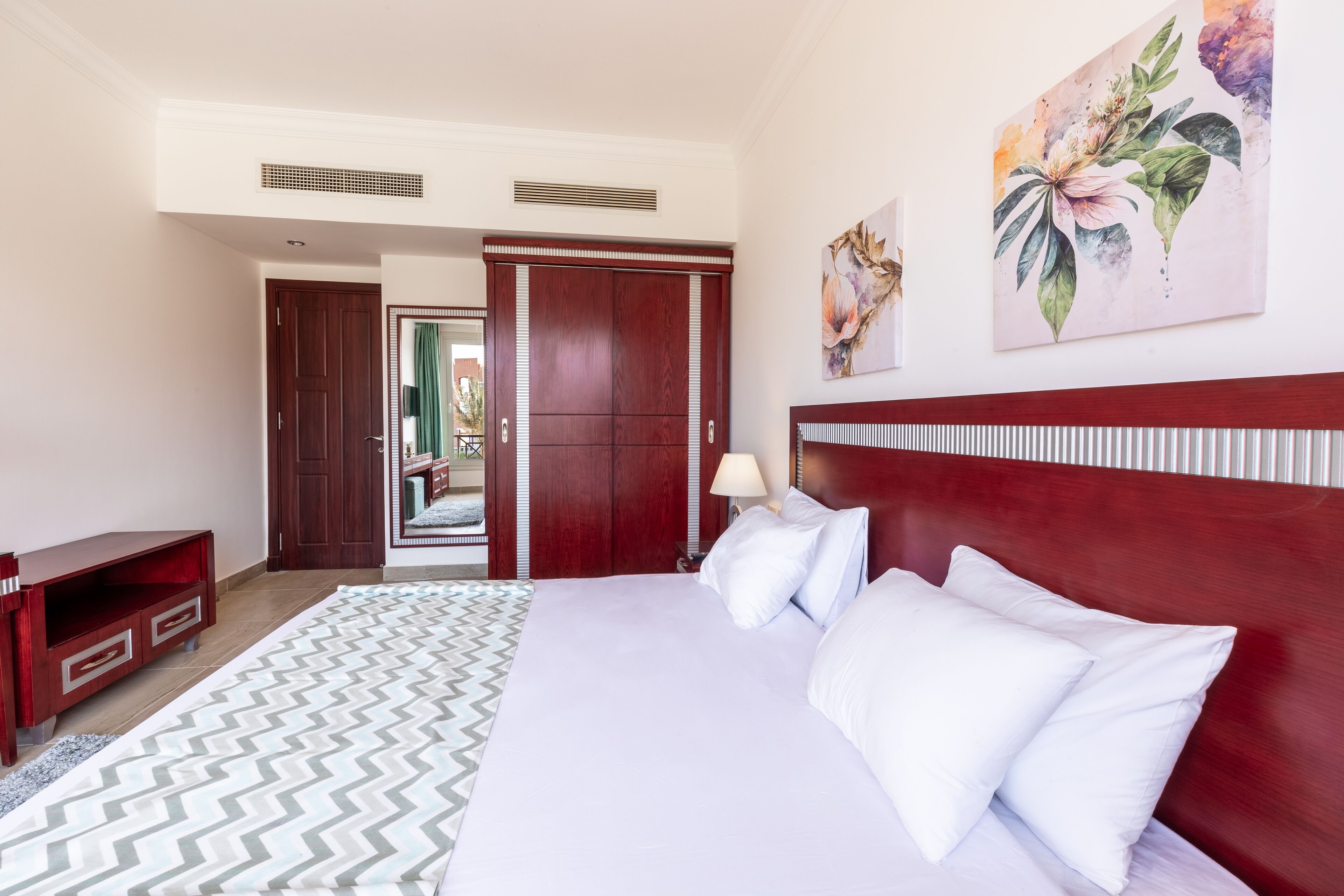 Habitación de hotel con cama, escritorio, armario y baño visible a través de una puerta abierta.
