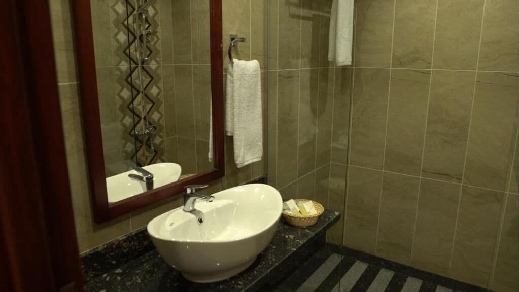 A bathroom with a white sink, a mirror, and a towel rack.