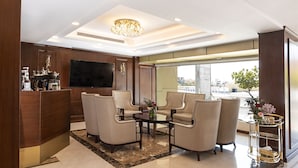 A modern hotel lobby with a reception desk, seating area, chandelier, and large windows offering a city view. - Laten Suites Prince sultan (Jeddah)