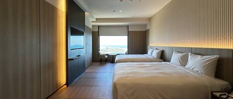 A modern hotel room with a large bed, a TV mounted on the wall, and a view of the city through a large window.