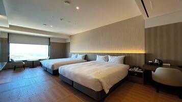 Habitación de hotel moderna con dos camas, un escritorio y vista al mar.