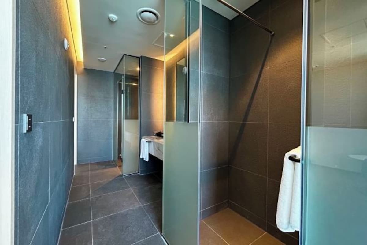 Un baño moderno con cabina de ducha de vidrio, zona de lavabo a la vista y un perchero para toallas.