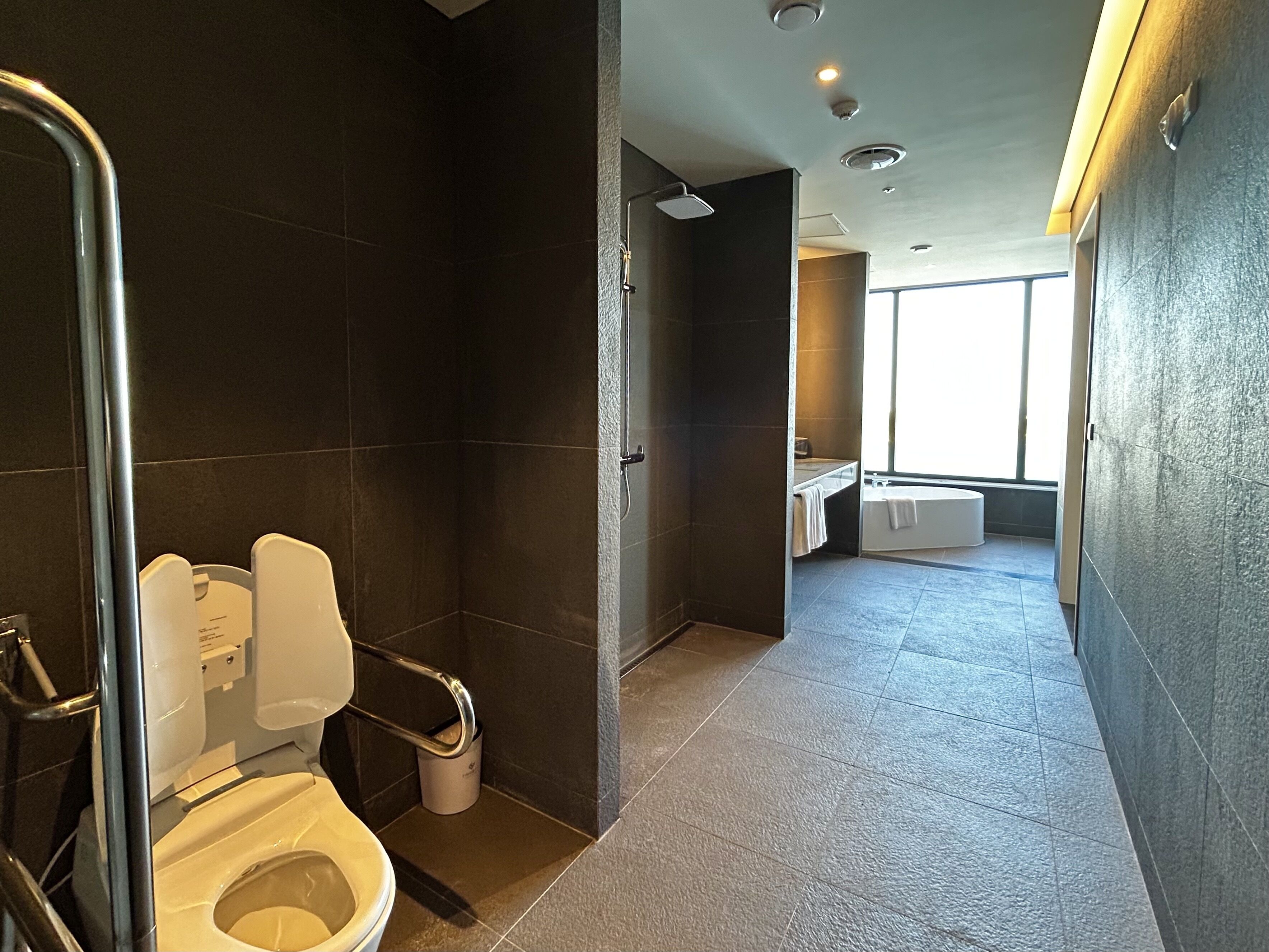 A modern bathroom with a toilet, shower, and sink.
