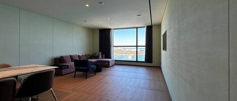 A modern living room with a large window, a sofa, a coffee table, and a dining area with a table and chairs.
