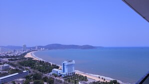 Un paysage urbain côtier avec un hôtel imposant, une plage et un ciel dégagé.