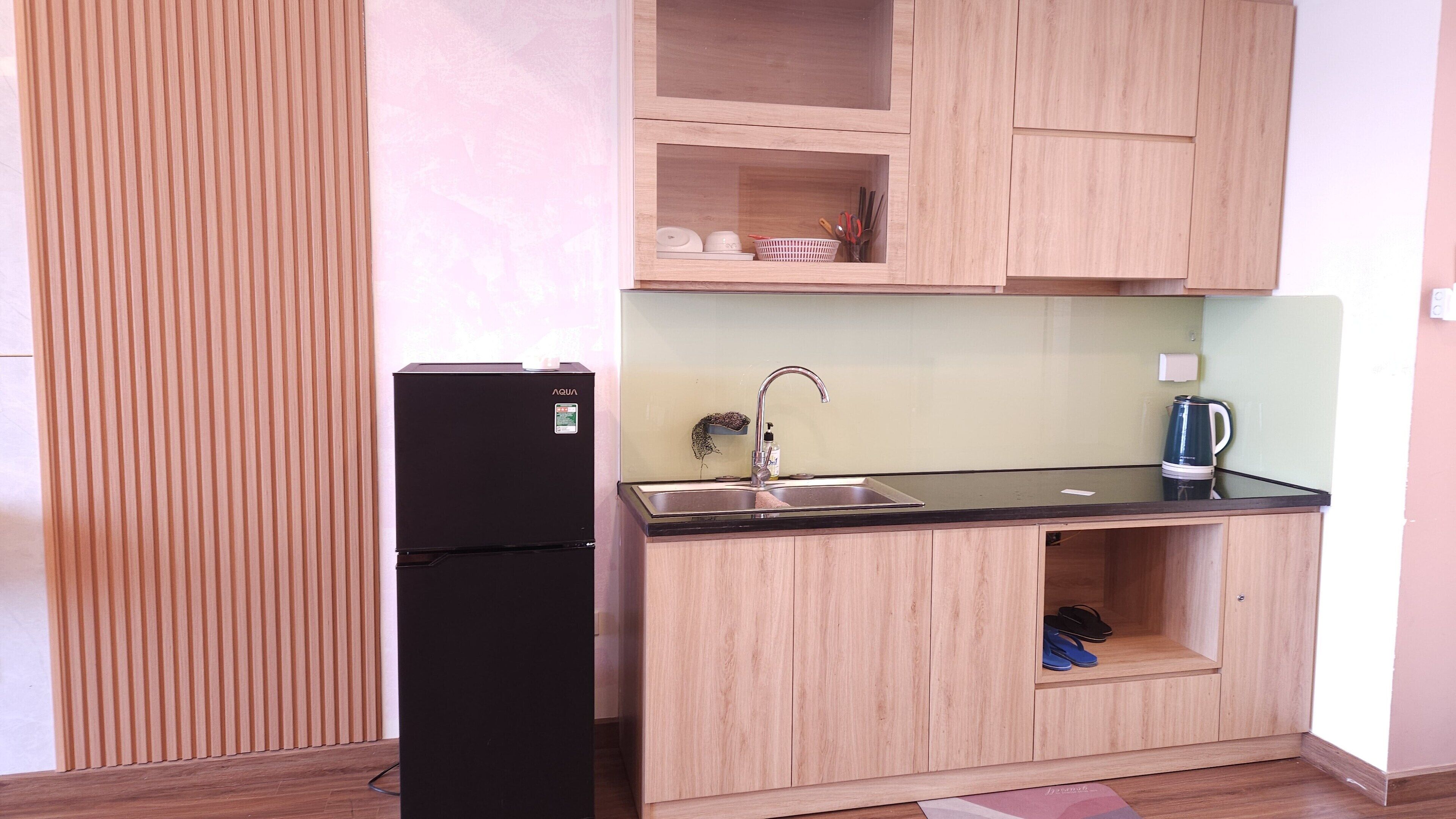 Eine kleine Küche mit einem schwarzen Kühlschrank, einer Spüle und einer Kaffeemaschine.