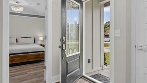 A bedroom with a bed, a chandelier, and a door leading to a balcony.
