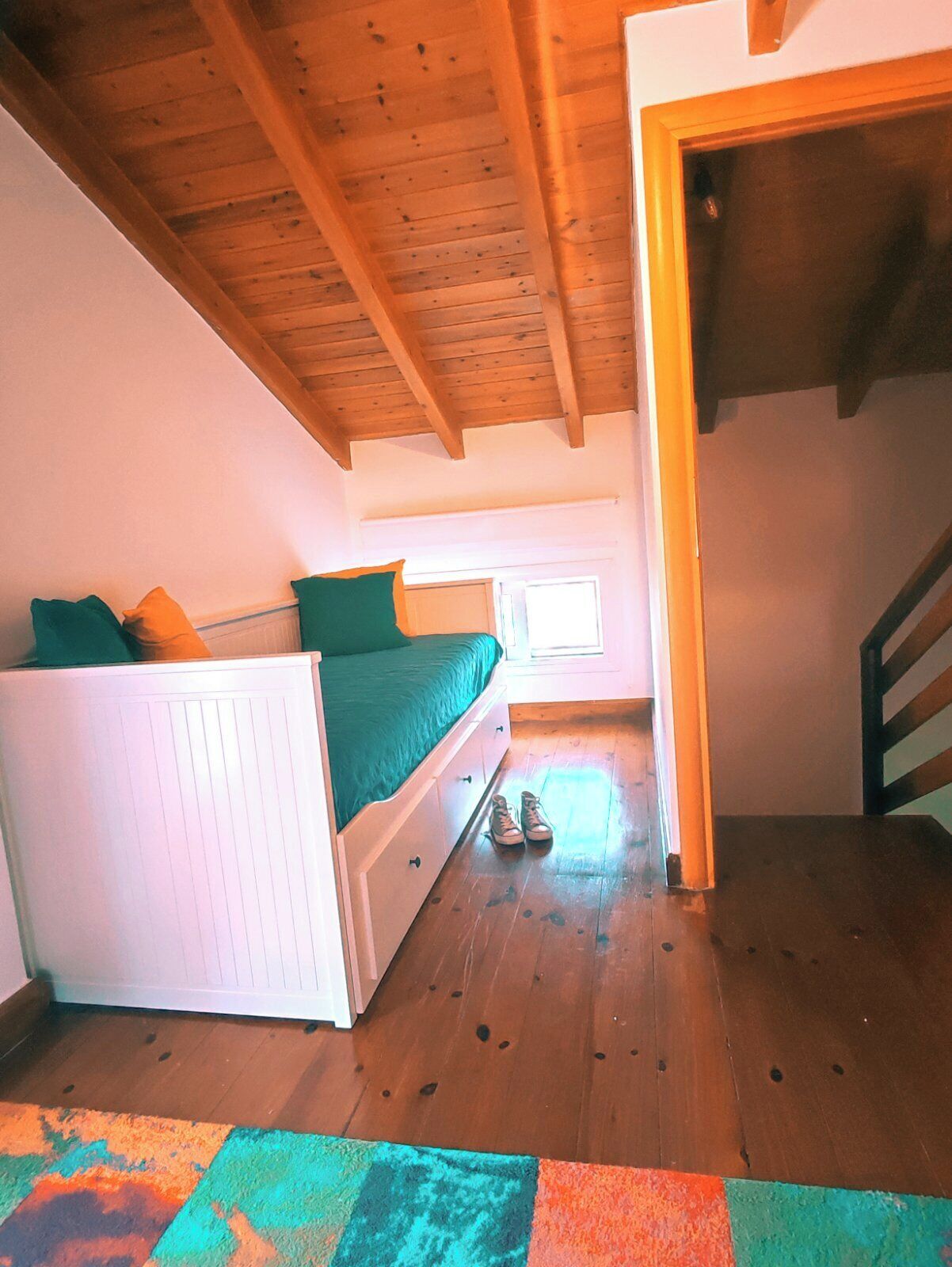 A bedroom with a bed, a dresser, a window, and a staircase.