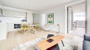A modern apartment with a kitchen, dining area, and a balcony with a city view.