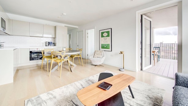 Eine moderne Wohnung mit Küche, Essbereich und einem Balkon mit Blick auf die Stadt.