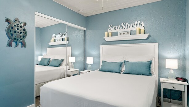 Un dormitorio con una cama grande, una mesita de noche, un espejo y un adorno en la pared.