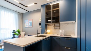 A modern kitchen with a white countertop, blue cabinets, and a built-in oven. - Radiant Nampo Hotel (Busan)