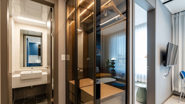 A modern bathroom with a glass partition, a sink, and a mirror. - Radiant Nampo Hotel (Busan)