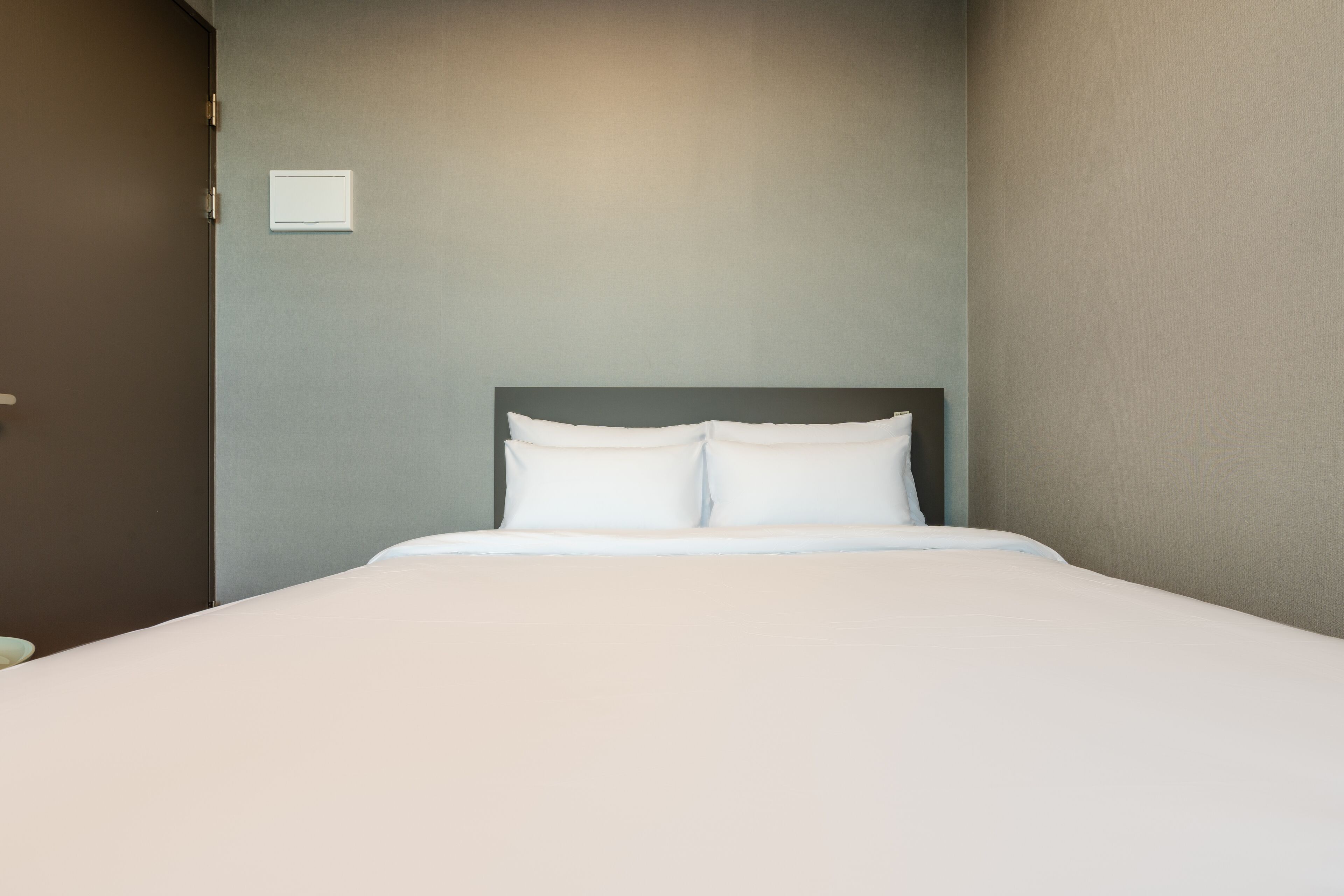 A neatly made bed with white linens in a hotel room.