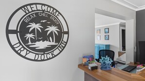 A reception desk with a welcome sign, a wooden desk, a blue chair, and a small blue coral decoration. - King Room Hotel- 2 Pools, Near Beach/Boardwalk, No Pets Allowed (Carolina Beach)