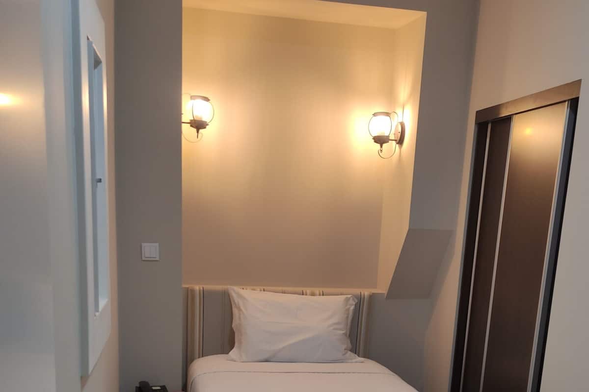 Un dormitorio moderno con una cama, lámparas de noche, una mesita de noche y una puerta.