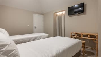 A hotel room with two beds, a television mounted on the wall, and a wooden desk.