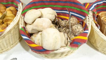 Ein Korb voller verschiedener Backwaren, darunter Brot und Kekse, auf einem Tisch.