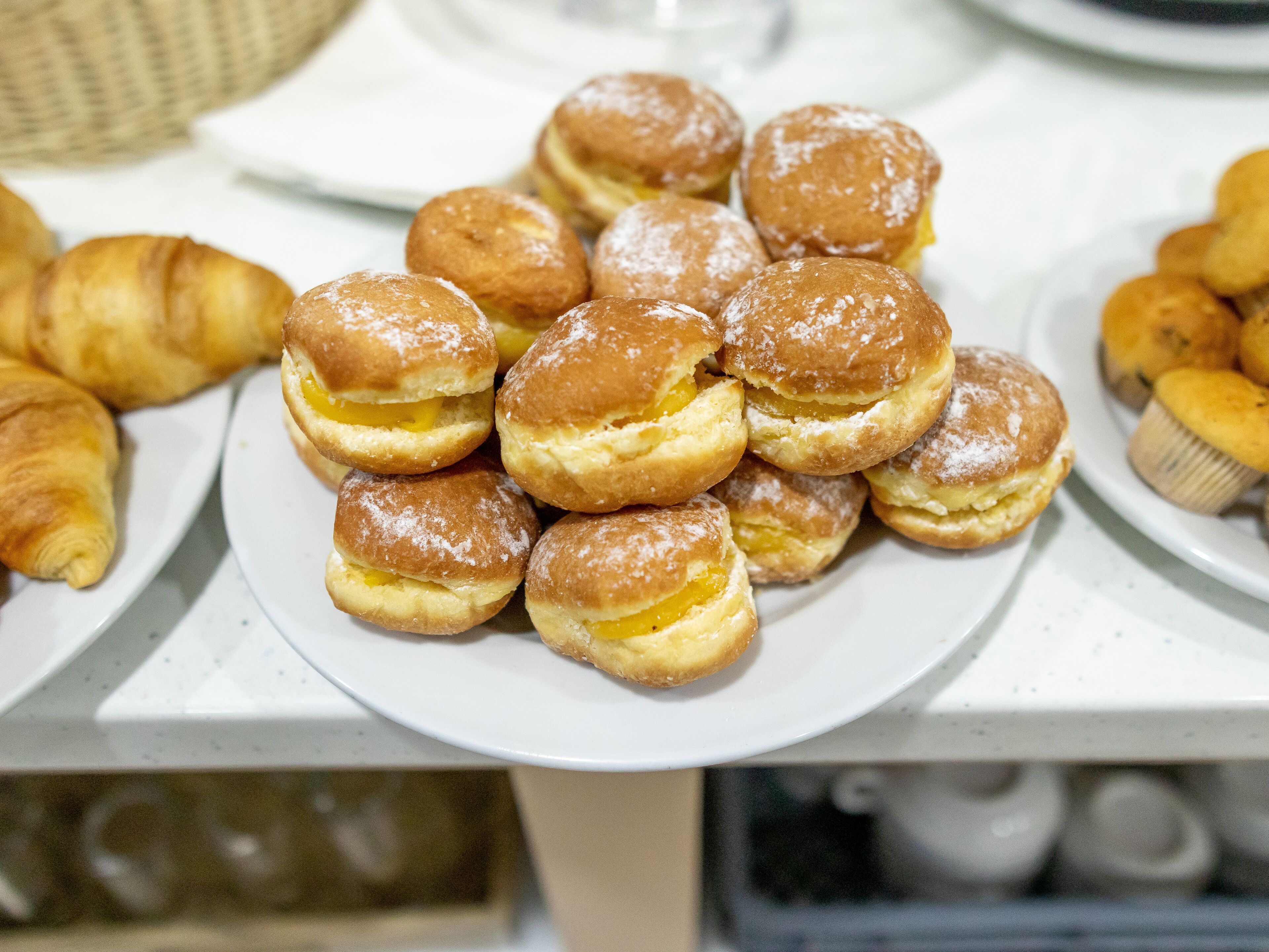Une assiette de choux à la crème sur une table blanche.