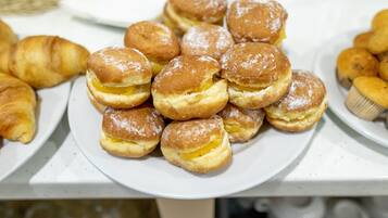 Une assiette de choux à la crème sur une table blanche.