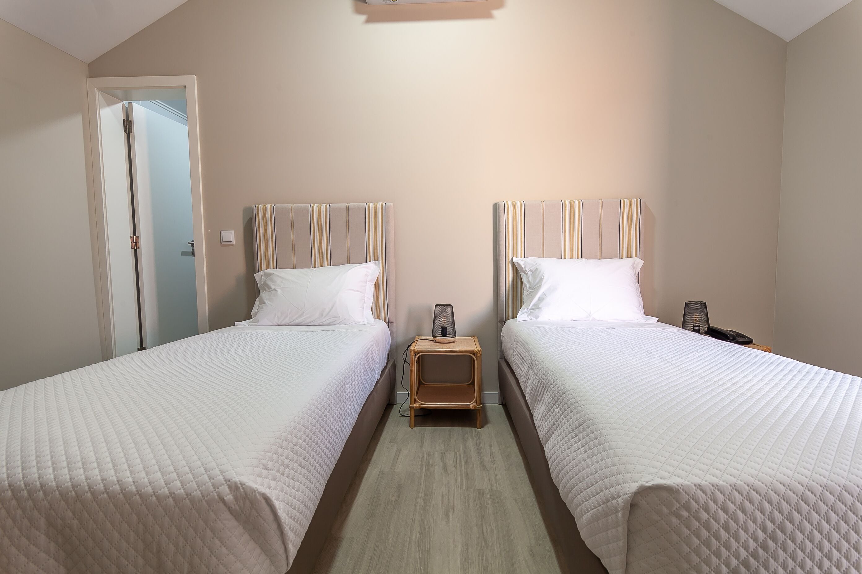 A bedroom with two beds, a bedside table, and a nightstand.