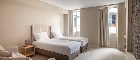 A bedroom with two beds, a nightstand, a chair, and a stone accent wall.