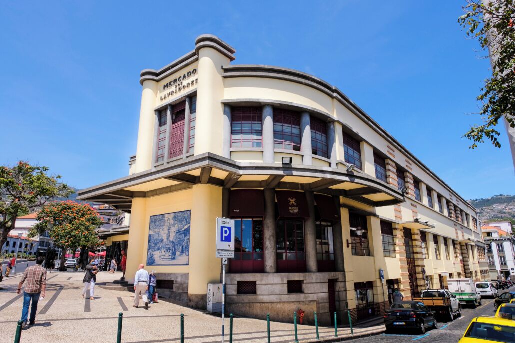 Un edificio histórico con fachada curva, una entrada destacada y un letrero de estacionamiento azul.