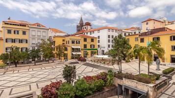 A plaza with buildings, a church tower, and a café.