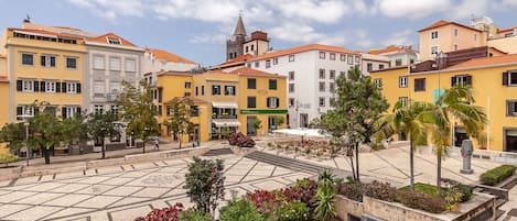 A plaza with buildings, a church tower, and a café.