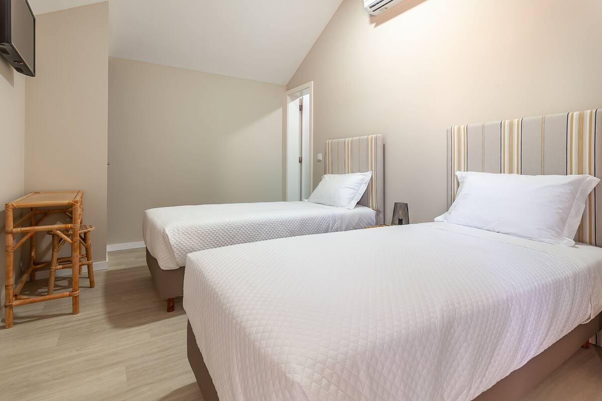 Una habitación de hotel con dos camas, una silla de madera y un televisor.