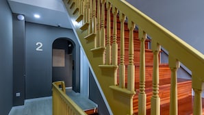 Uma escadaria com balaústres e corrimão de madeira, que leva a um patamar com uma porta marcada com o número '2'.