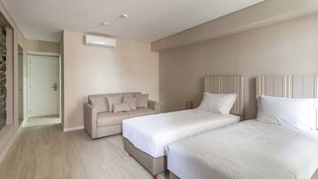 A bedroom with a bed, a sofa, and a door leading to another room.