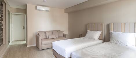 A bedroom with a bed, a sofa, and a door leading to another room.