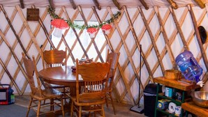 Un intérieur chaleureux avec une table à manger en bois, des chaises et un mur décoratif orné d’un motif en treillis.