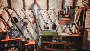 Une cuisine rustique avec des étagères en bois, une bouilloire et divers ustensiles de cuisine.