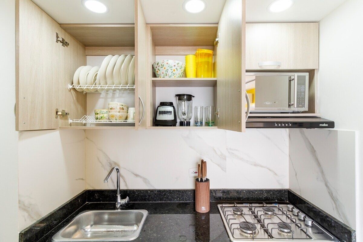 Una cocina pequeña con un lavabo, estufa y armarios.