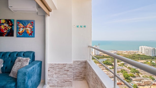 A balcony with a view of the sea, a blue sofa, and two butterfly paintings. - Primi (Cartagena)