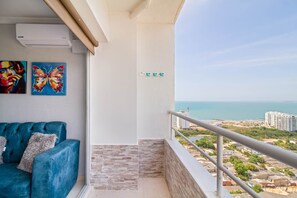 A balcony with a view of the sea, a blue sofa, and two butterfly paintings. - Primi (Cartagena)