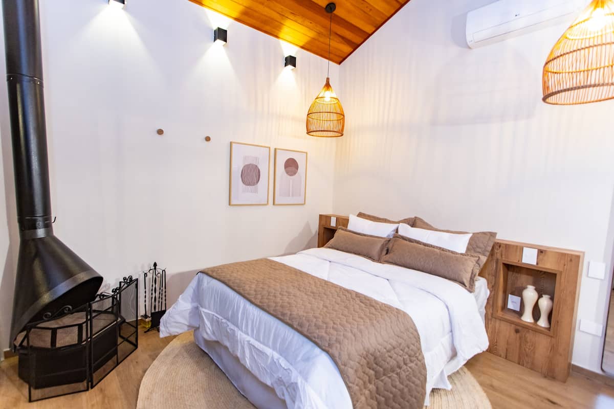 Een slaapkamer met een bed, een houten hoofdbord, een wandheater en een hanglamp.