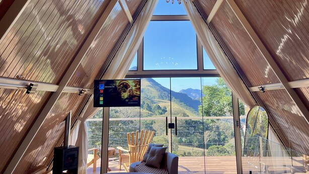 Quarto moderno com grande janela e vista para as montanhas, televisão de tela plana e um espaço de estar acolhedor.