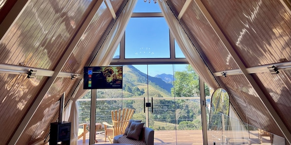 Una habitación moderna con un amplio ventanal que ofrece vistas a la montaña, un televisor de pantalla plana y una zona de estar acogedora.