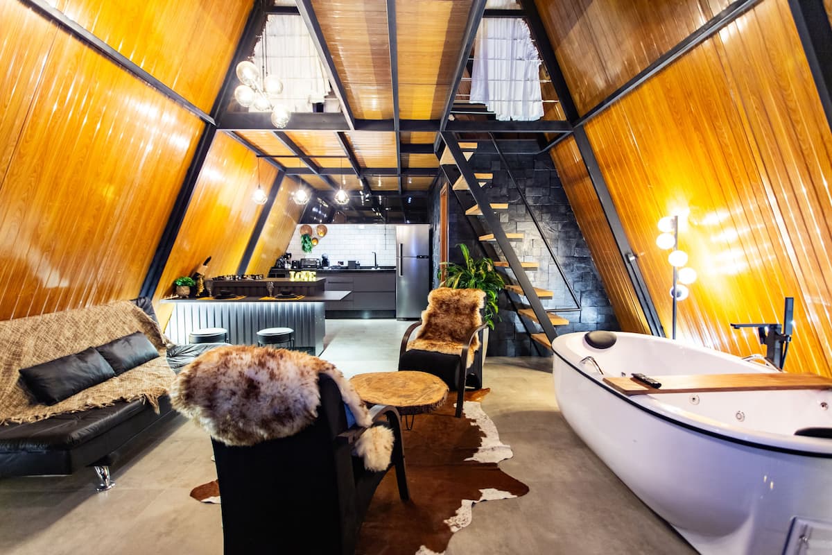 Een gezellig interieur met een bank, een stoel, een klein rond tafeltje, een boot en een trap naar een hoger gelegen verdieping.
