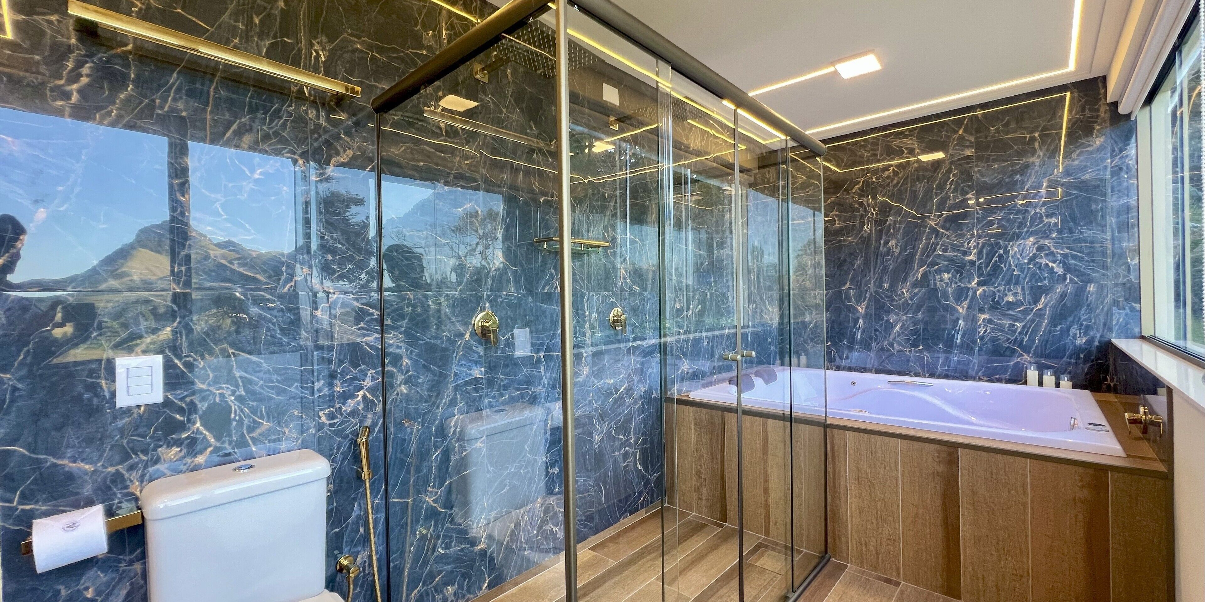 Ein modernes Badezimmer mit einer gläsernen Duschkabine, einem Holzbadezimmermöbel und einer marmorierten Wand.