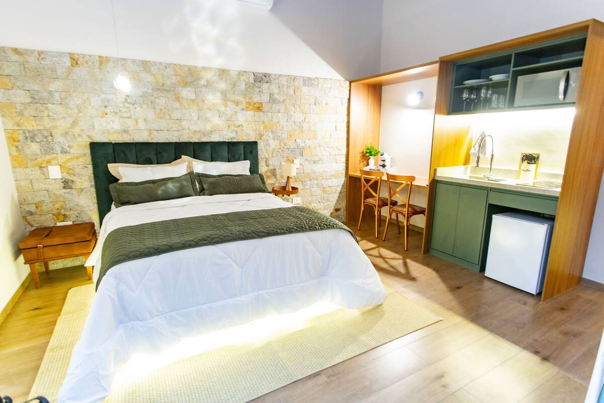Een slaapkamer met een bed, een bureau en een kitchenette.