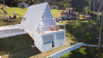 Une maison moderne avec un toit en pente, un balcon doté de chaises en bois et une petite terrasse.