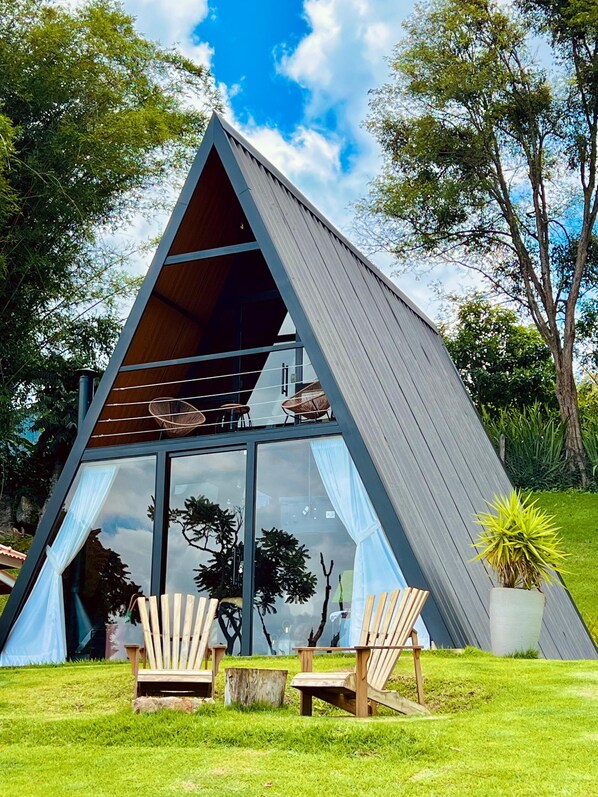 Un bâtiment moderne de forme triangulaire, doté d’une façade en verre, de chaises longues en bois et d’une plante en pot.