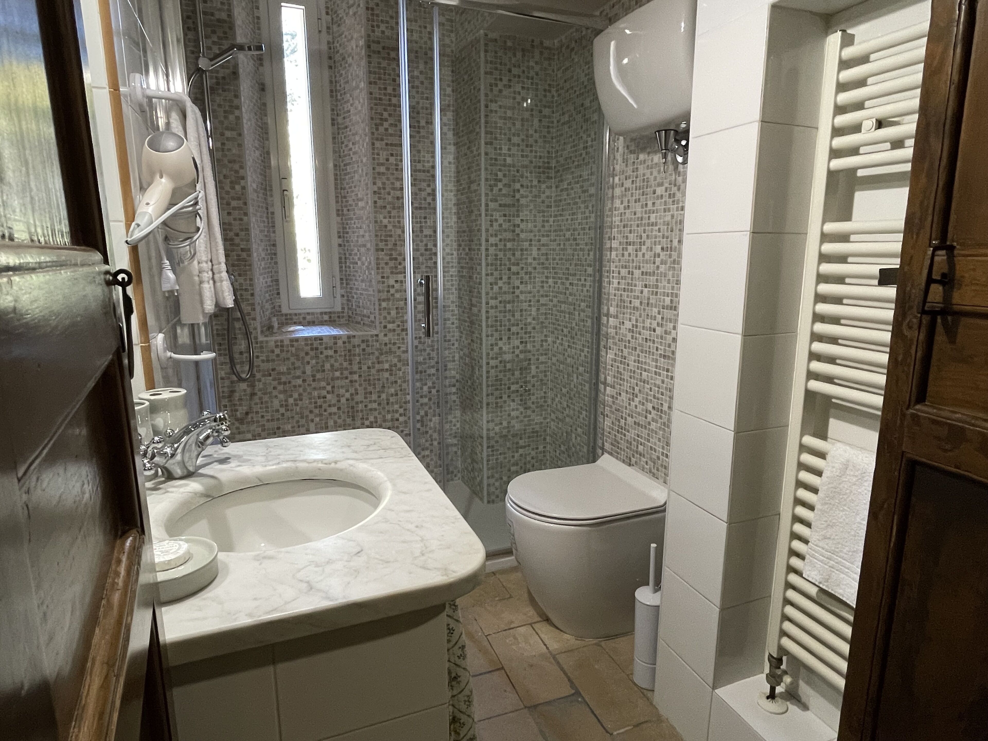 A bathroom with a marble sink, a toilet, a shower with a glass door, and a towel rack.