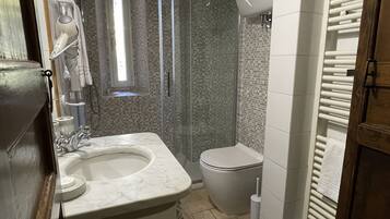 A bathroom with a marble sink, a toilet, a shower with a glass door, and a towel rack.