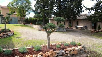 A courtyard with a stone wall, a tree, and a building with a tiled roof.